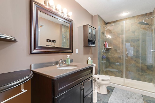 full bathroom with vanity, a textured ceiling, toilet, and a shower stall