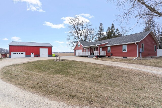 ranch-style home featuring an outdoor structure, a front lawn, a shingled roof, a detached garage, and dirt driveway