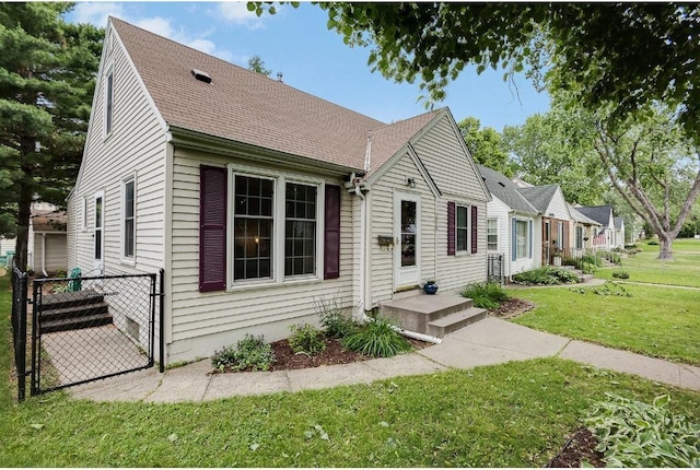 view of front of home with a front lawn, roof with shingles, fence, and a gate