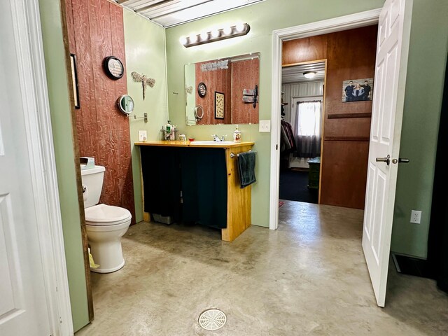 bathroom with concrete flooring, toilet, and vanity