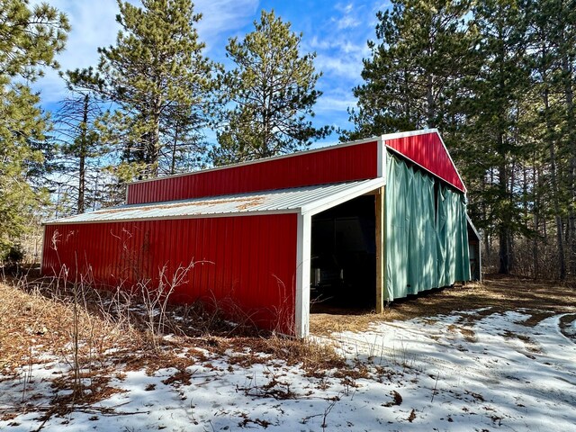 snow covered structure with an outbuilding and a pole building