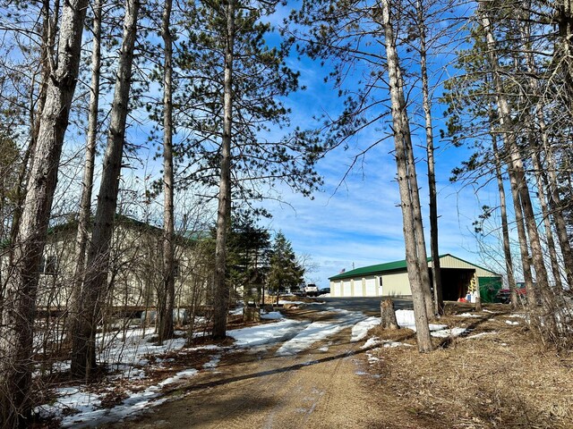 view of snowy exterior featuring an outbuilding and driveway