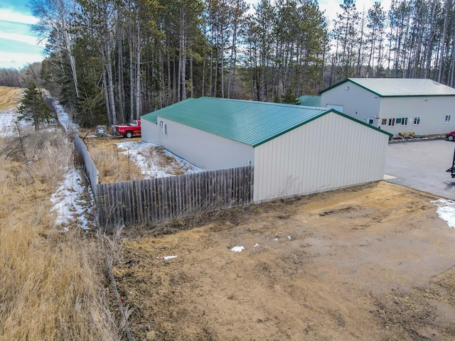 view of home's exterior featuring an outbuilding, metal roof, and fence