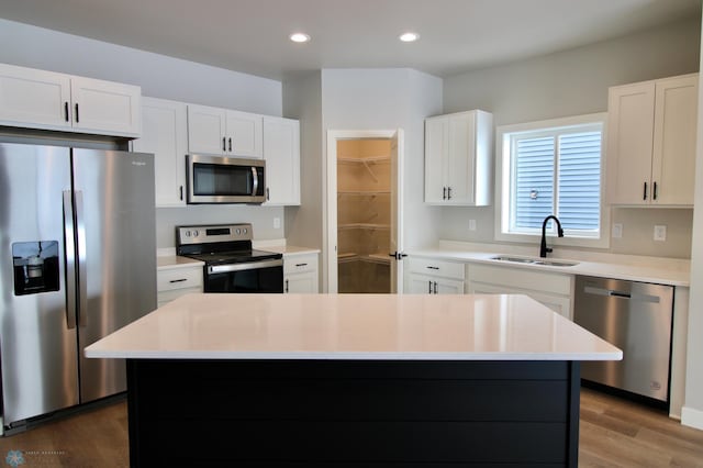 kitchen featuring stainless steel appliances, a kitchen island, sink, and white cabinets