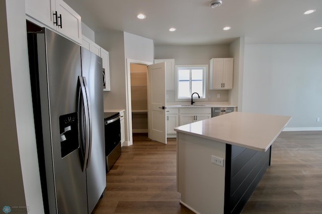 kitchen with sink, white cabinetry, dark hardwood / wood-style floors, a kitchen island, and stainless steel appliances