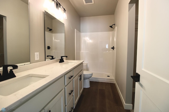 bathroom featuring hardwood / wood-style flooring, vanity, toilet, and a shower