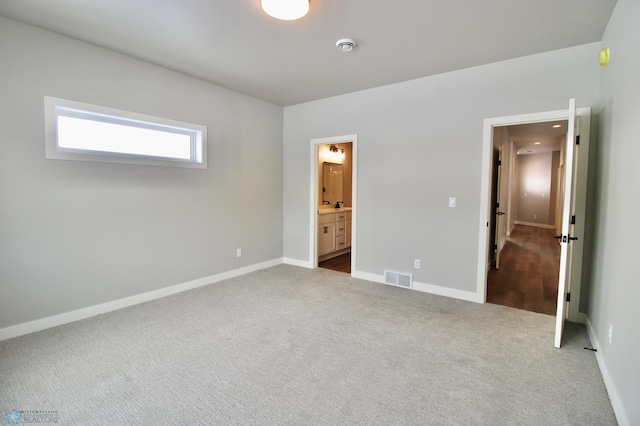 unfurnished bedroom featuring ensuite bath and carpet