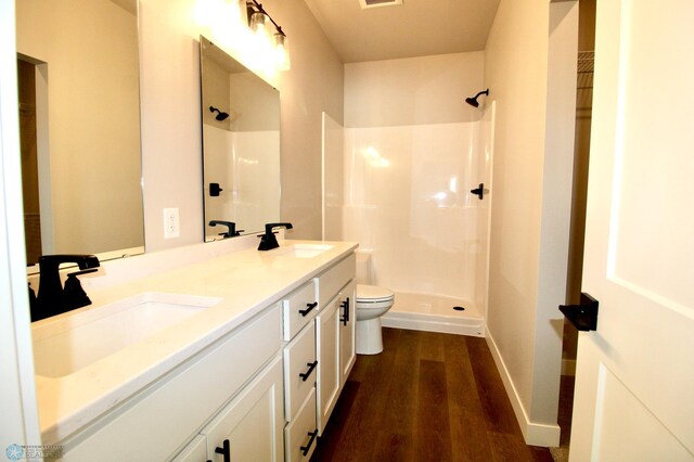 bathroom featuring hardwood / wood-style flooring, vanity, toilet, and walk in shower