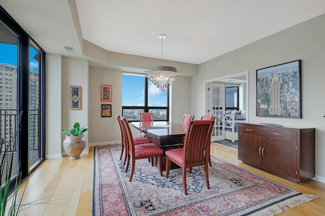 dining area with light wood-type flooring and a notable chandelier