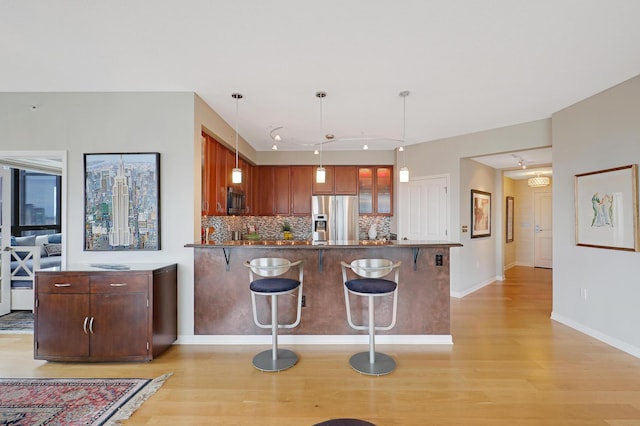 kitchen featuring rail lighting, hanging light fixtures, light hardwood / wood-style flooring, tasteful backsplash, and stainless steel appliances