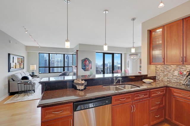 kitchen featuring kitchen peninsula, stainless steel dishwasher, hanging light fixtures, and sink