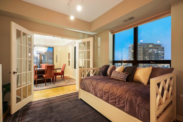 bedroom featuring an inviting chandelier, wood-type flooring, and french doors