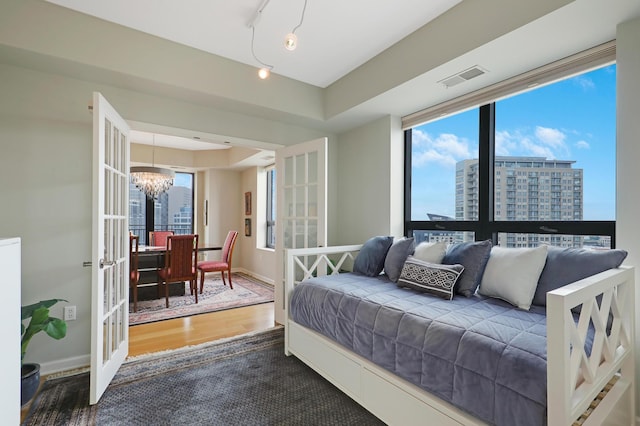 bedroom with a chandelier, french doors, and hardwood / wood-style flooring