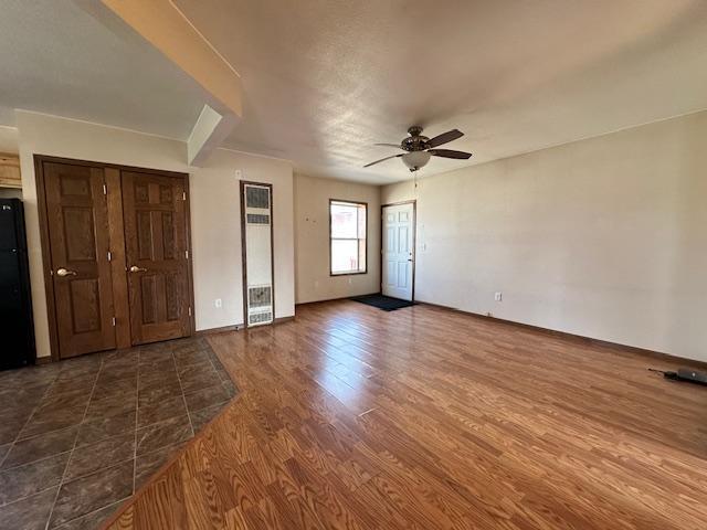 unfurnished bedroom with black refrigerator, dark hardwood / wood-style flooring, and ceiling fan