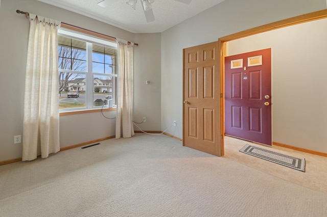 foyer entrance with light carpet, ceiling fan, and a textured ceiling