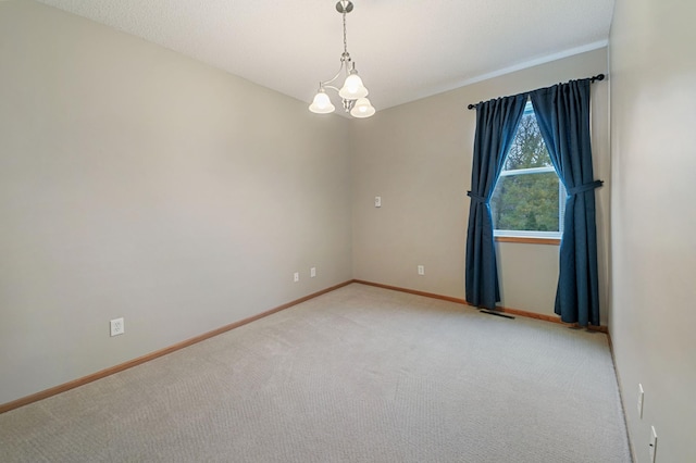 spare room featuring carpet and a notable chandelier