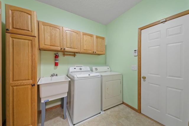 laundry area featuring cabinets, a textured ceiling, and separate washer and dryer