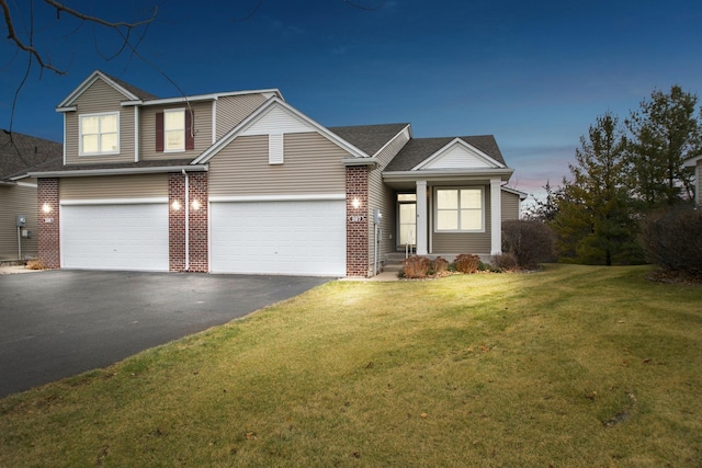 traditional-style house with brick siding, driveway, a front yard, and roof with shingles