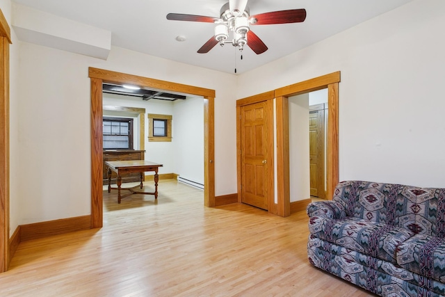 living area featuring ceiling fan, light wood-type flooring, and baseboard heating