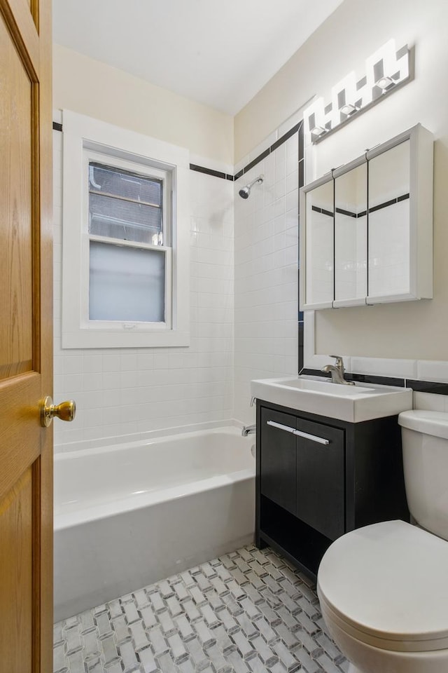 full bathroom featuring tiled shower / bath, vanity, toilet, and tile patterned floors