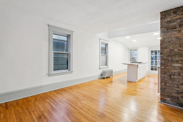 interior space with vaulted ceiling, radiator, and light hardwood / wood-style floors