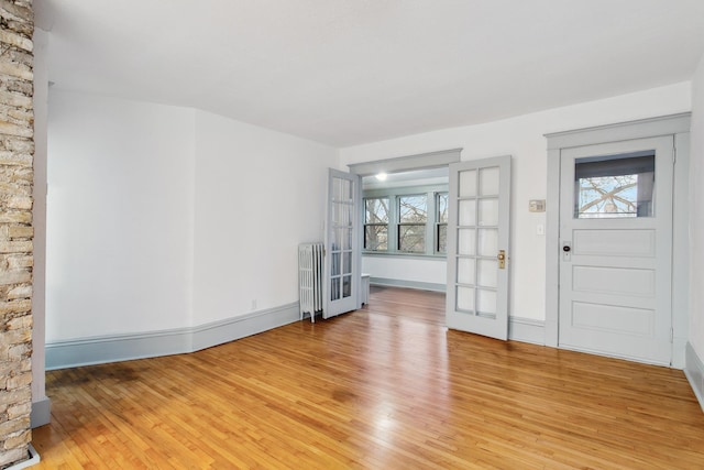 foyer entrance with radiator, a wealth of natural light, and light hardwood / wood-style floors