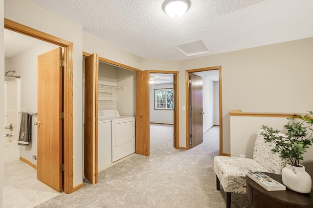 hallway with light colored carpet, washer and dryer, and a textured ceiling