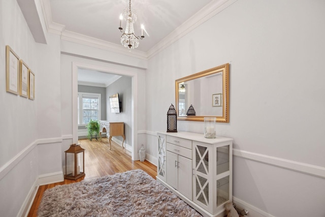 hall featuring a notable chandelier, ornamental molding, and light wood-type flooring