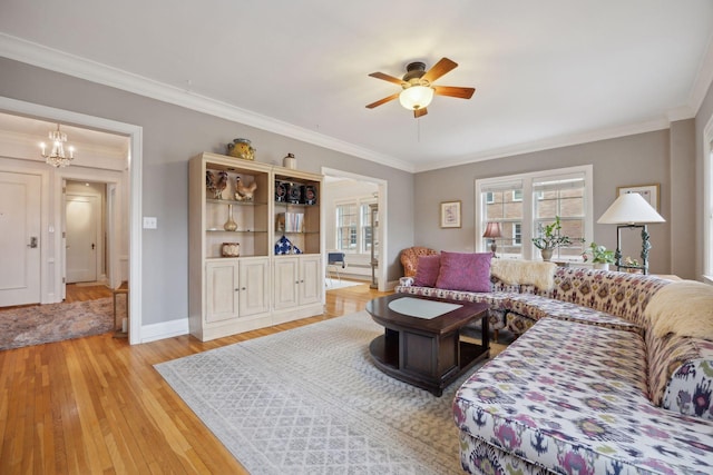 living room featuring ceiling fan with notable chandelier, ornamental molding, and light hardwood / wood-style floors