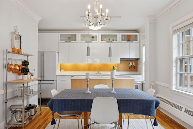 dining space with a chandelier, ornamental molding, radiator, and light hardwood / wood-style floors