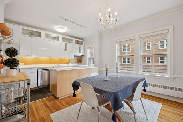 dining area with ornamental molding, radiator heating unit, a notable chandelier, and light wood-type flooring