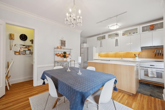 dining room featuring crown molding, track lighting, light hardwood / wood-style floors, and a notable chandelier