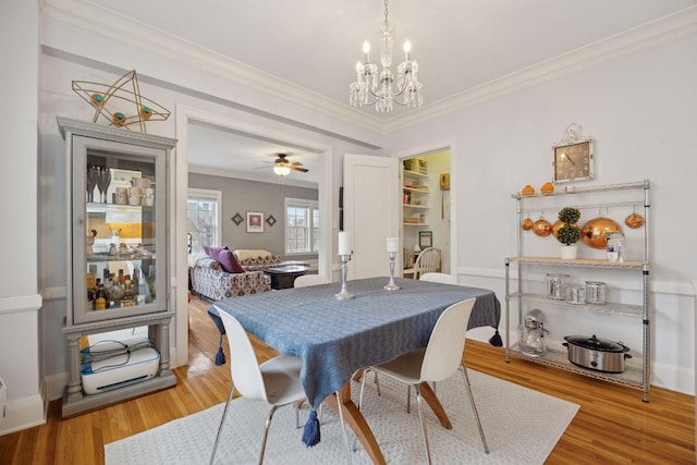 dining space with hardwood / wood-style flooring, ornamental molding, and ceiling fan with notable chandelier