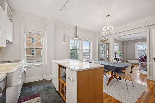 kitchen with white cabinetry, crown molding, pendant lighting, and dark hardwood / wood-style flooring