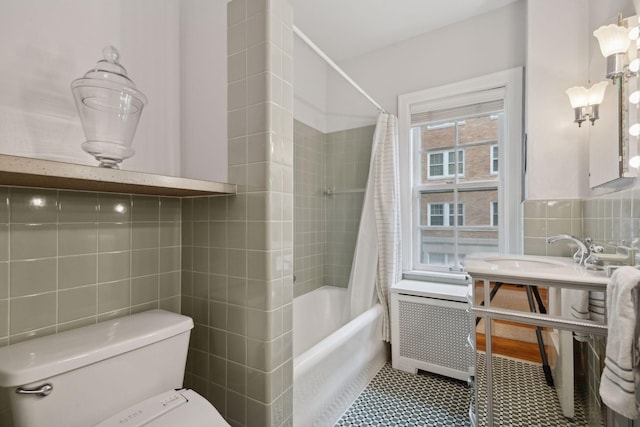 full bathroom with radiator, sink, tile walls, toilet, and shower / bath combo with shower curtain