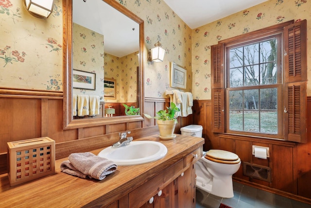 bathroom with vanity, toilet, a healthy amount of sunlight, and tile patterned floors