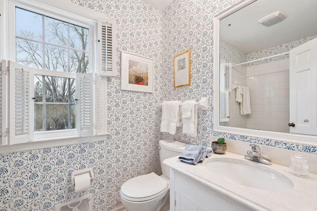 bathroom with vanity, toilet, and a tile shower