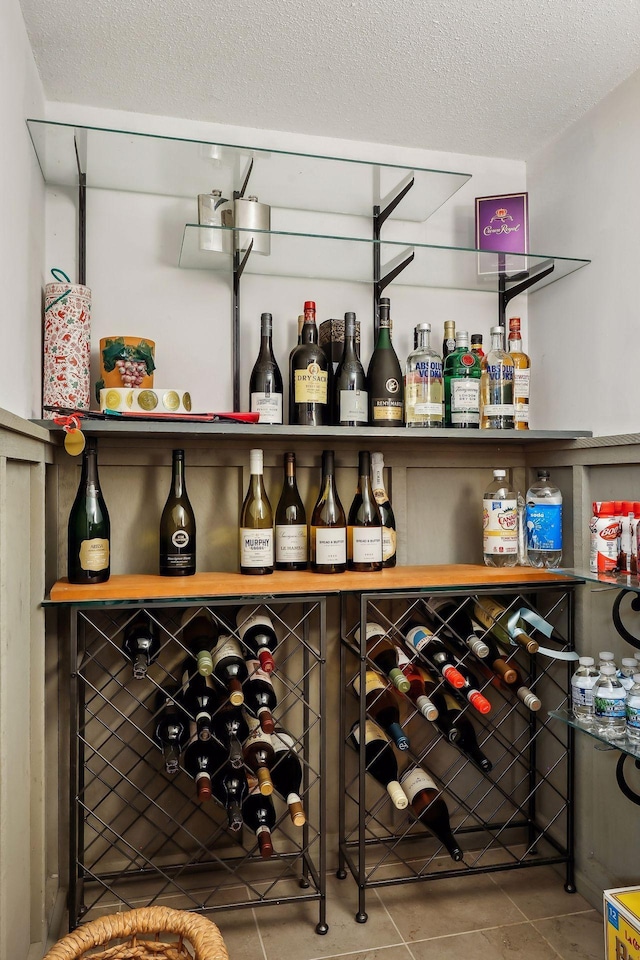 wine room with bar area, a textured ceiling, and tile patterned flooring