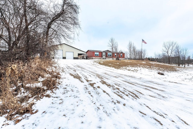 yard layered in snow featuring a garage and an outdoor structure