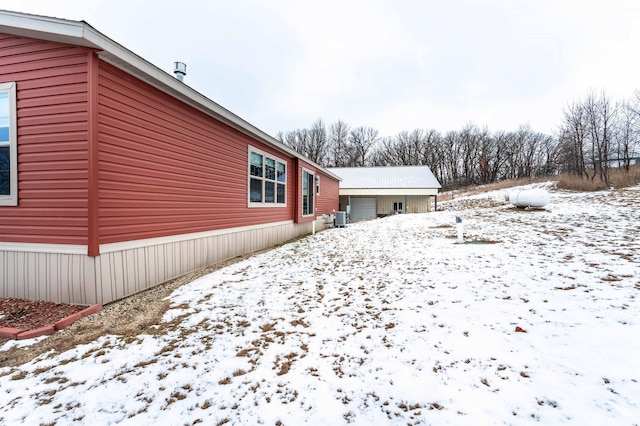 snow covered property featuring a garage and cooling unit