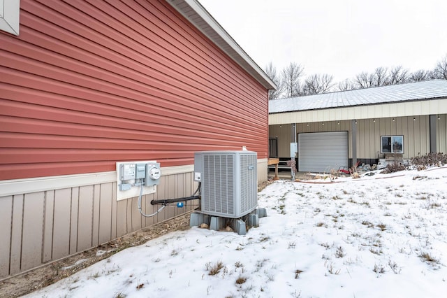 view of snowy exterior featuring central AC and an outdoor structure