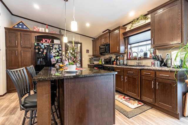 kitchen with black appliances, a kitchen island, dark stone countertops, and light hardwood / wood-style floors