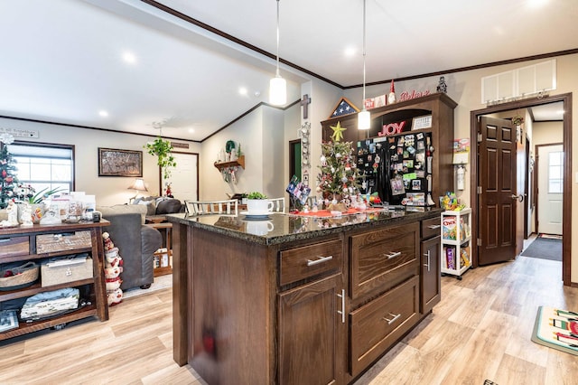 kitchen with a center island, dark stone countertops, pendant lighting, light hardwood / wood-style floors, and ornamental molding