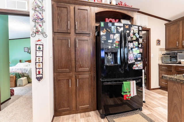 kitchen featuring light hardwood / wood-style flooring, black fridge, dark stone counters, and crown molding