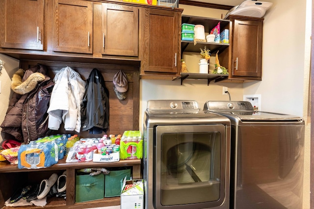 clothes washing area with cabinets, crown molding, and washing machine and clothes dryer