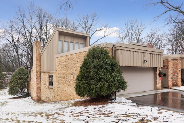 view of snowy exterior with a garage and central AC