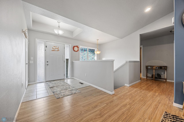 foyer with light hardwood / wood-style floors and a raised ceiling