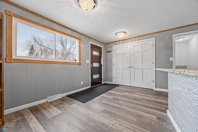 entrance foyer featuring hardwood / wood-style floors, crown molding, and an inviting chandelier