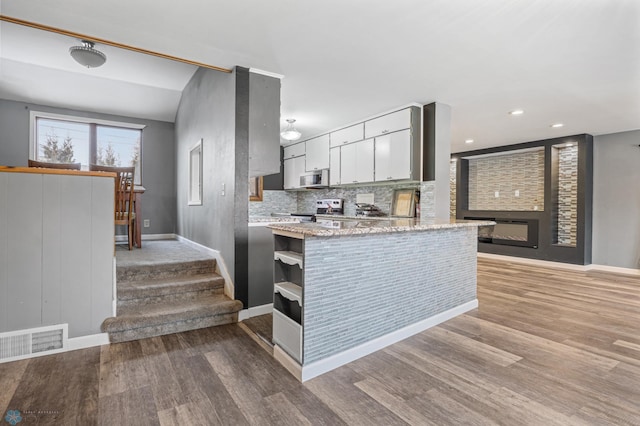 kitchen featuring white cabinets, appliances with stainless steel finishes, light wood-type flooring, and tasteful backsplash