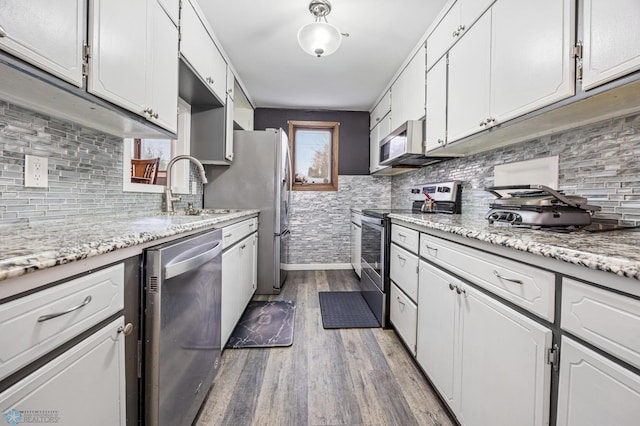 kitchen with white cabinets, sink, light hardwood / wood-style flooring, light stone counters, and stainless steel appliances